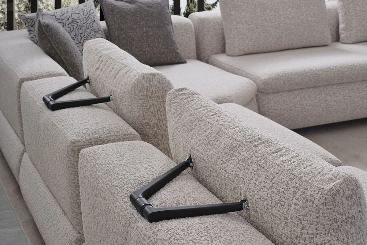 Detailed view of the Aura sofa upholstery, curved arm profile and coordinated neutral cushions