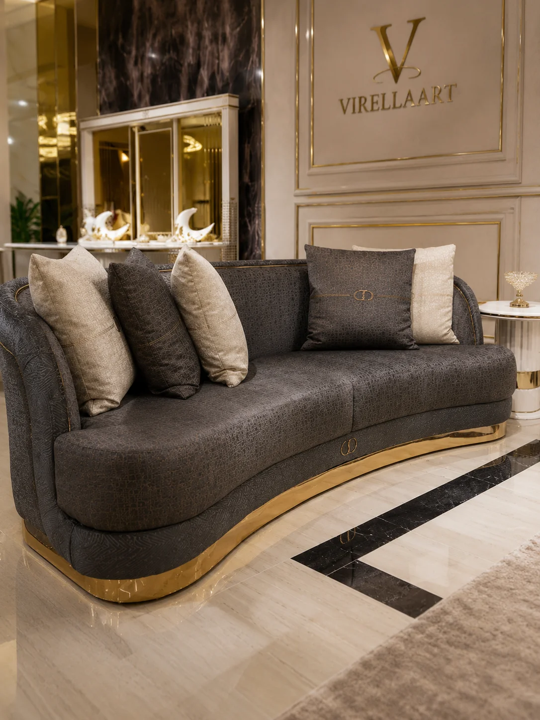 Deluxe charcoal curved sofa with layered ivory cushions and a polished gold-tone base
