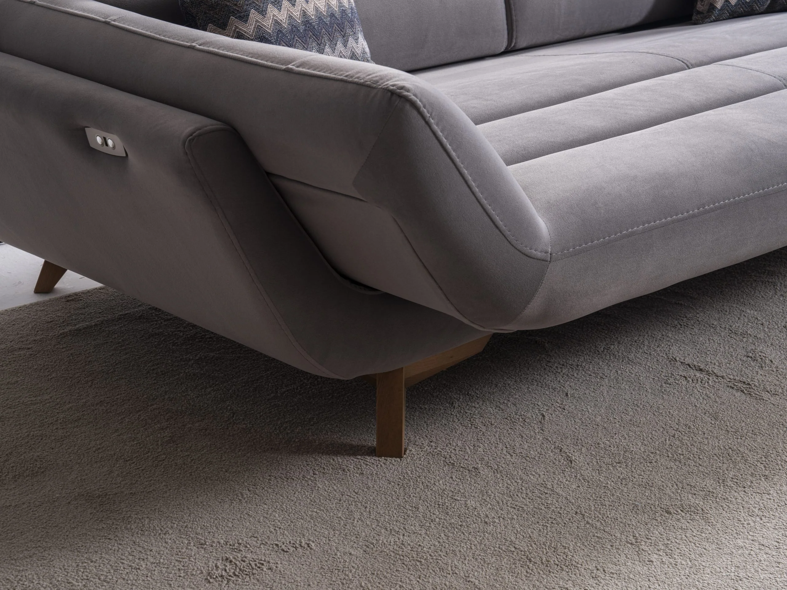 EFTELYA sofa side detail showing the upholstered arm structure and dark tapered leg