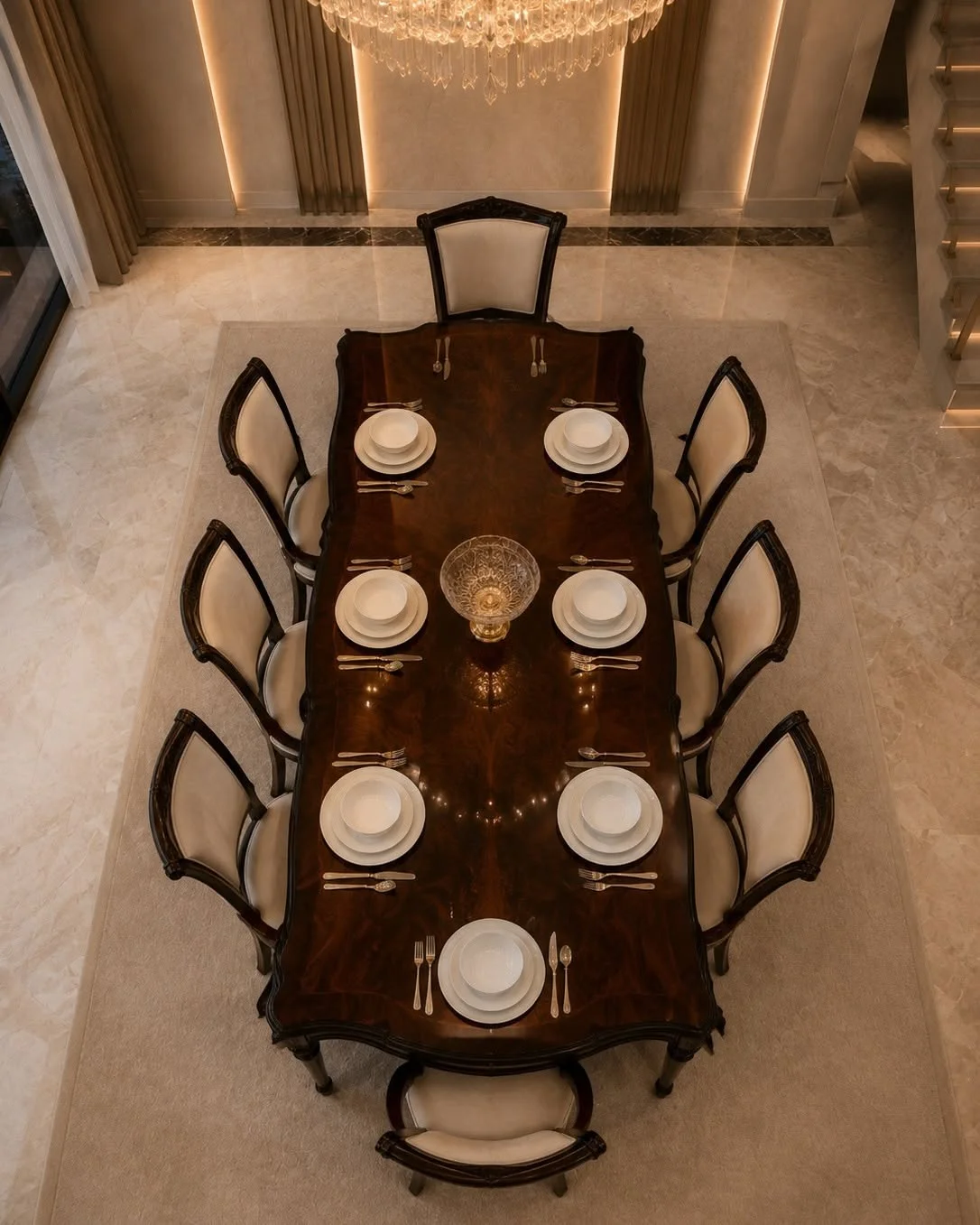 Overhead view of the Valdera rectangular dining table set for eight with cream upholstered chairs and a glossy walnut-toned top