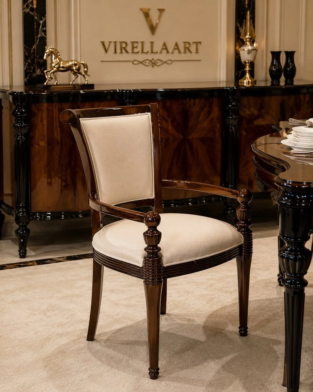 Valdera cream upholstered dining armchair with curved dark wood arms, turned front posts and matching sideboard in the background